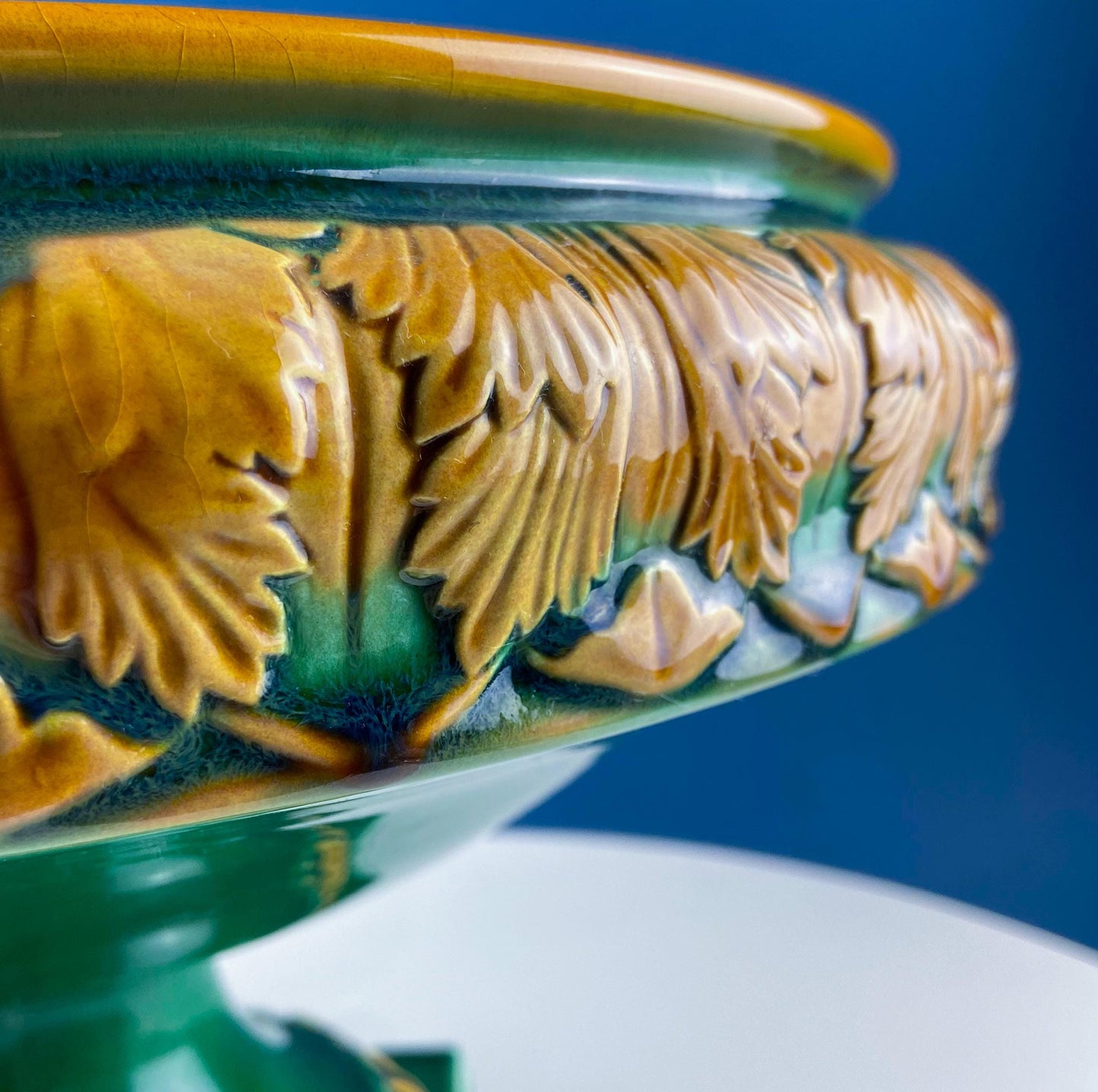 Close-up of a ceramic vase with detailed floral patterns on a blue background