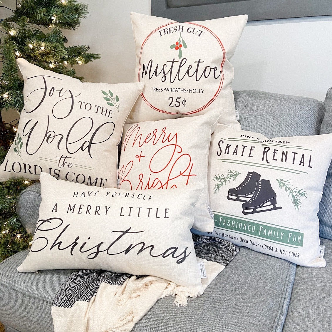 Merry and Bright Cursive Pillow Cover 17x17 inch featured among holiday-themed decorative pillows on a couch.