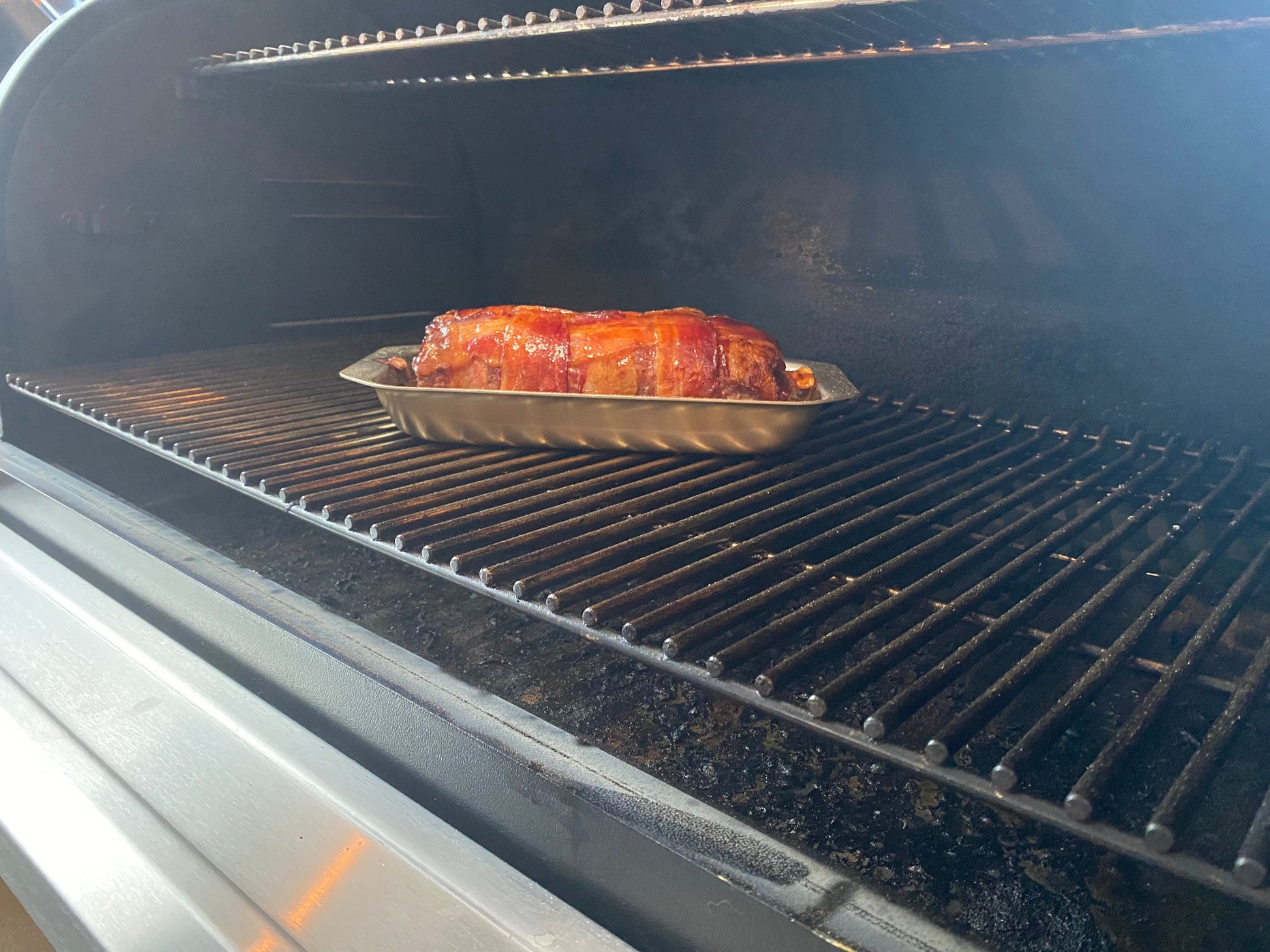 Roasted bacon wrapped meatloaf in an oven with smoke rising