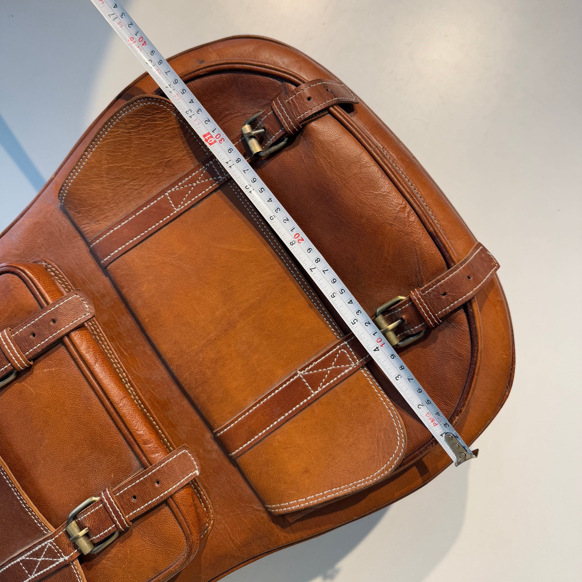 Brown leather bag with a measuring tape on a white background