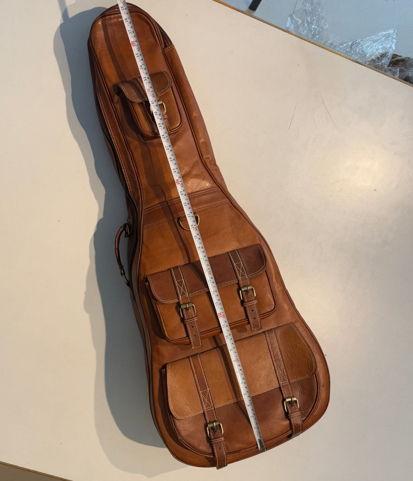 Brown leather guitar case on a light beige surface