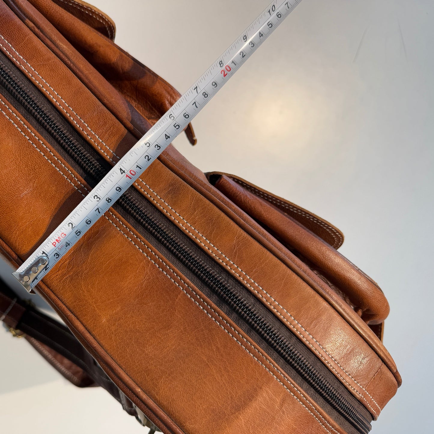 Brown leather briefcase with a measuring tape on a white background