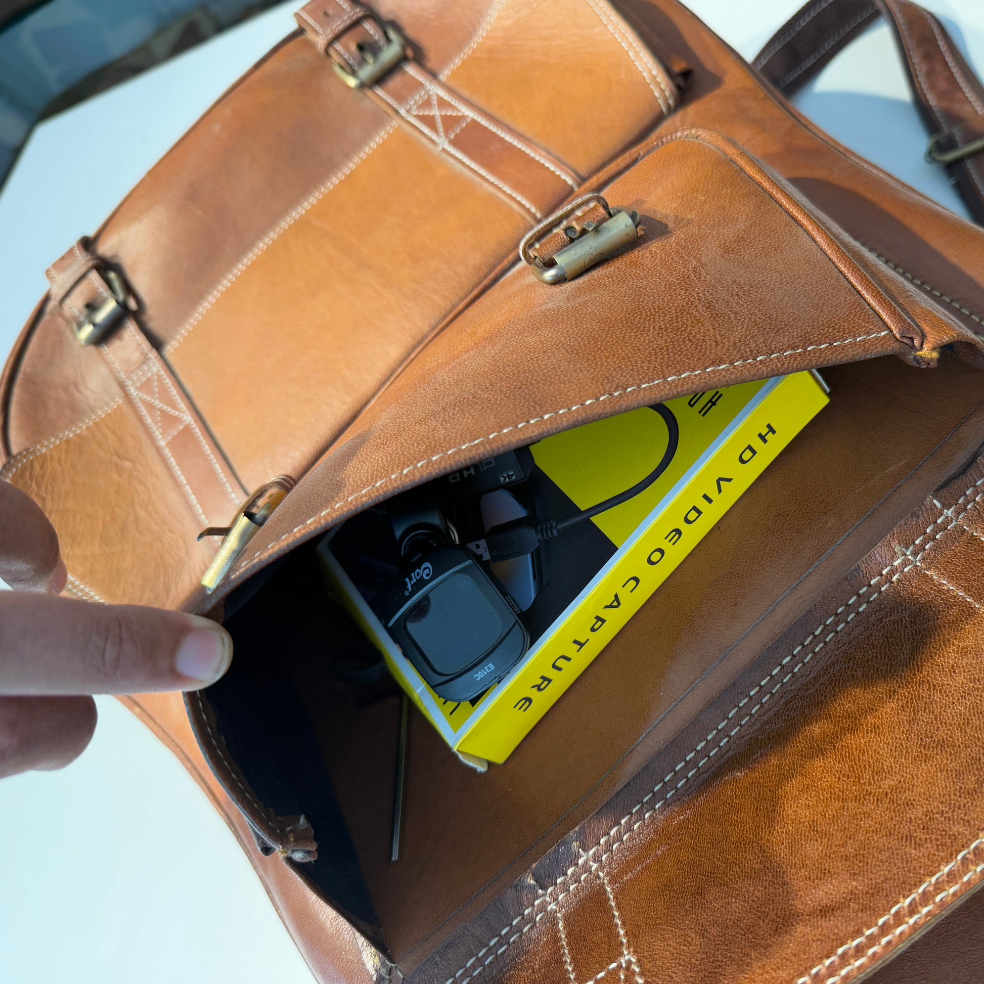 Brown leather bag with a yellow video capture device inside