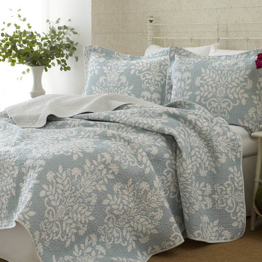 Bed with floral-patterned bedding and pillows in a bedroom setting.