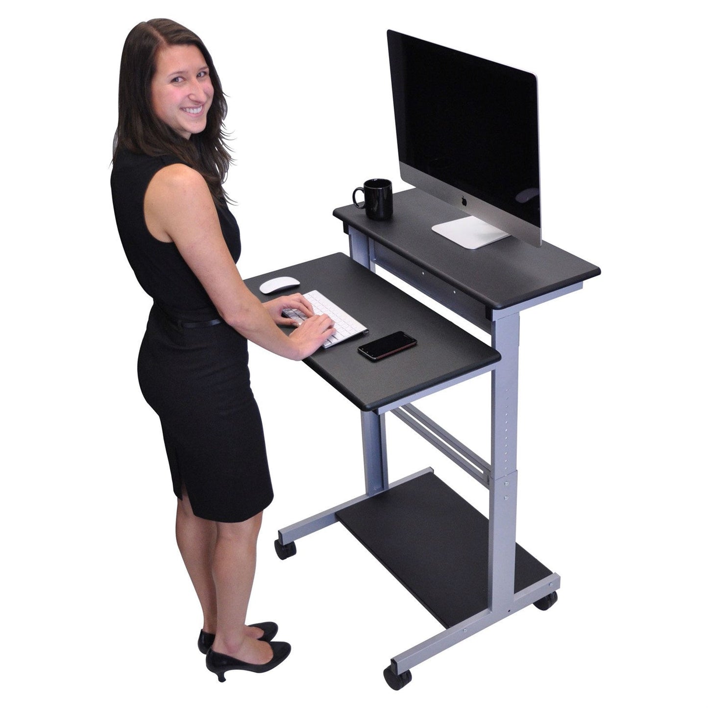 Woman using a standing desk with a computer setup on a white background