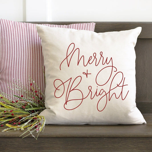 Merry and Bright Cursive Pillow Cover 17x17 inch on a cozy couch with decorative pillows and greenery.