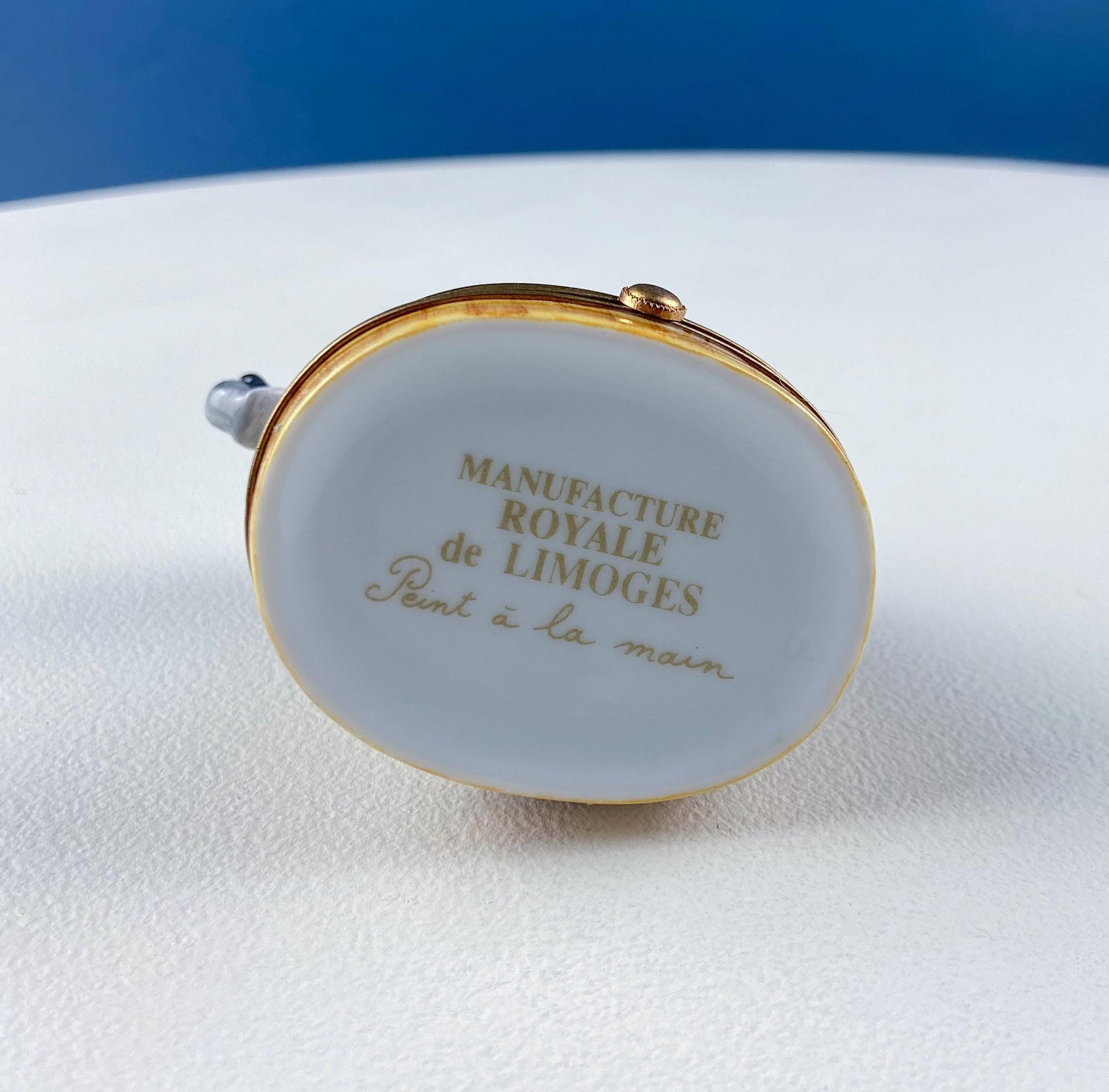 Limoges box with 'Manufacture Royale de Limoges' text on a white surface with blue background