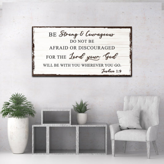 Living room with a Bible verse sign on the wall, potted plants, and a chair.