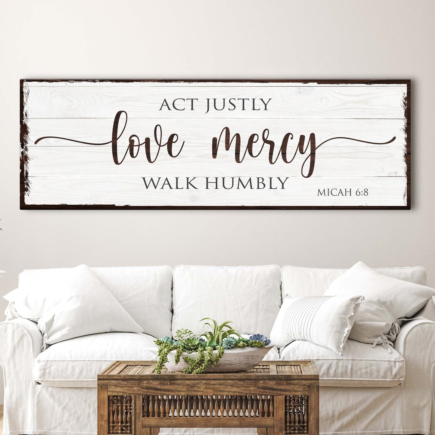 Decorative wall sign with Micah 6:8 Bible verse above a white sofa and wooden coffee table.