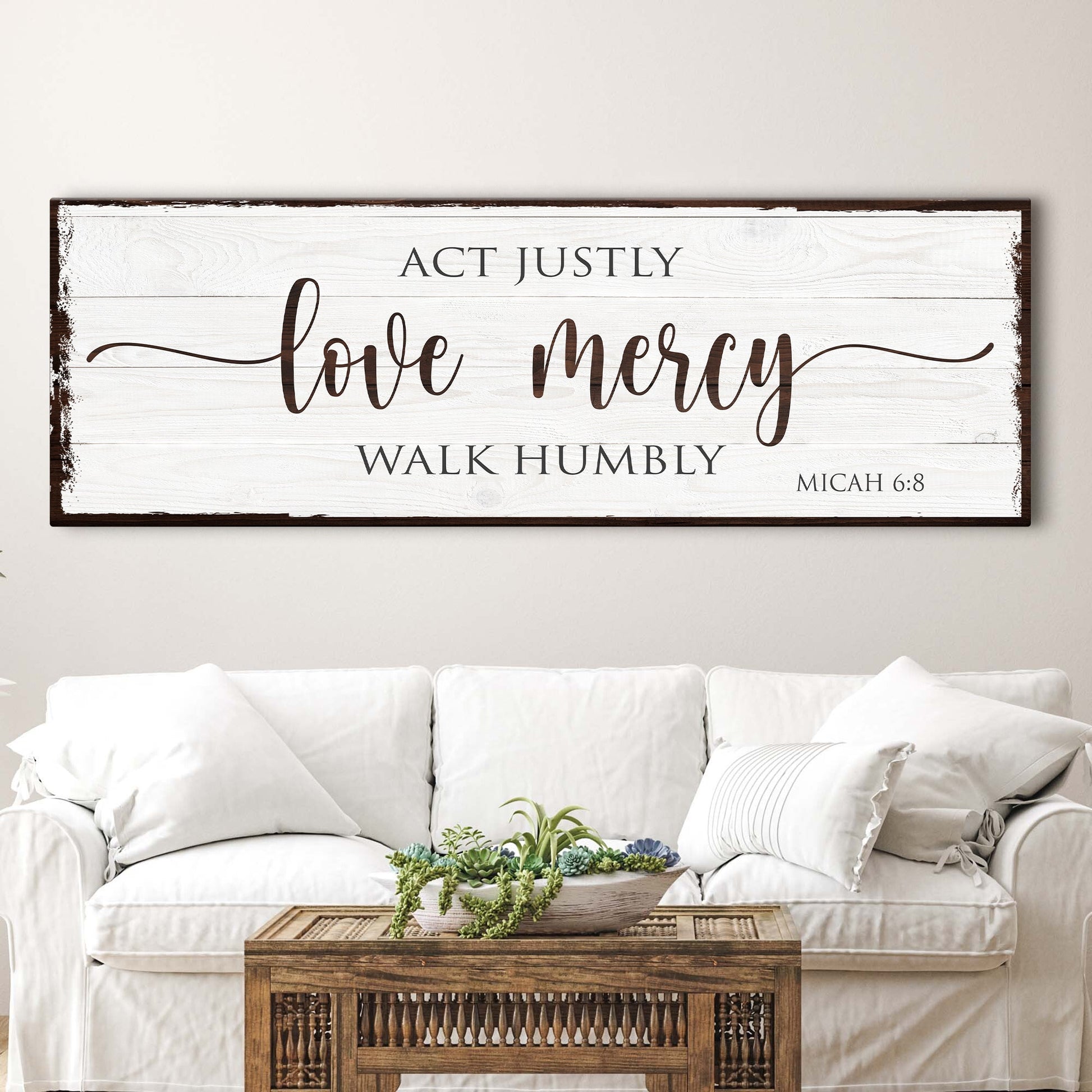 Decorative wall sign with Micah 6:8 Bible verse above a white sofa and wooden coffee table.