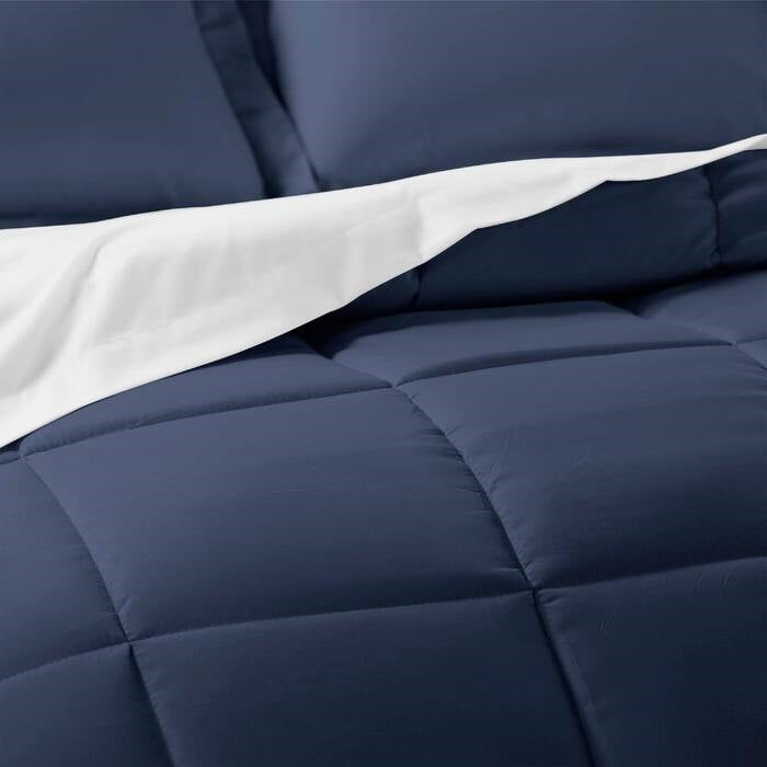 Twin Microfiber 6-Piece Reversible Bed-in-a-Bag Comforter Set Navy on a bed, featuring a navy comforter and white sheets.