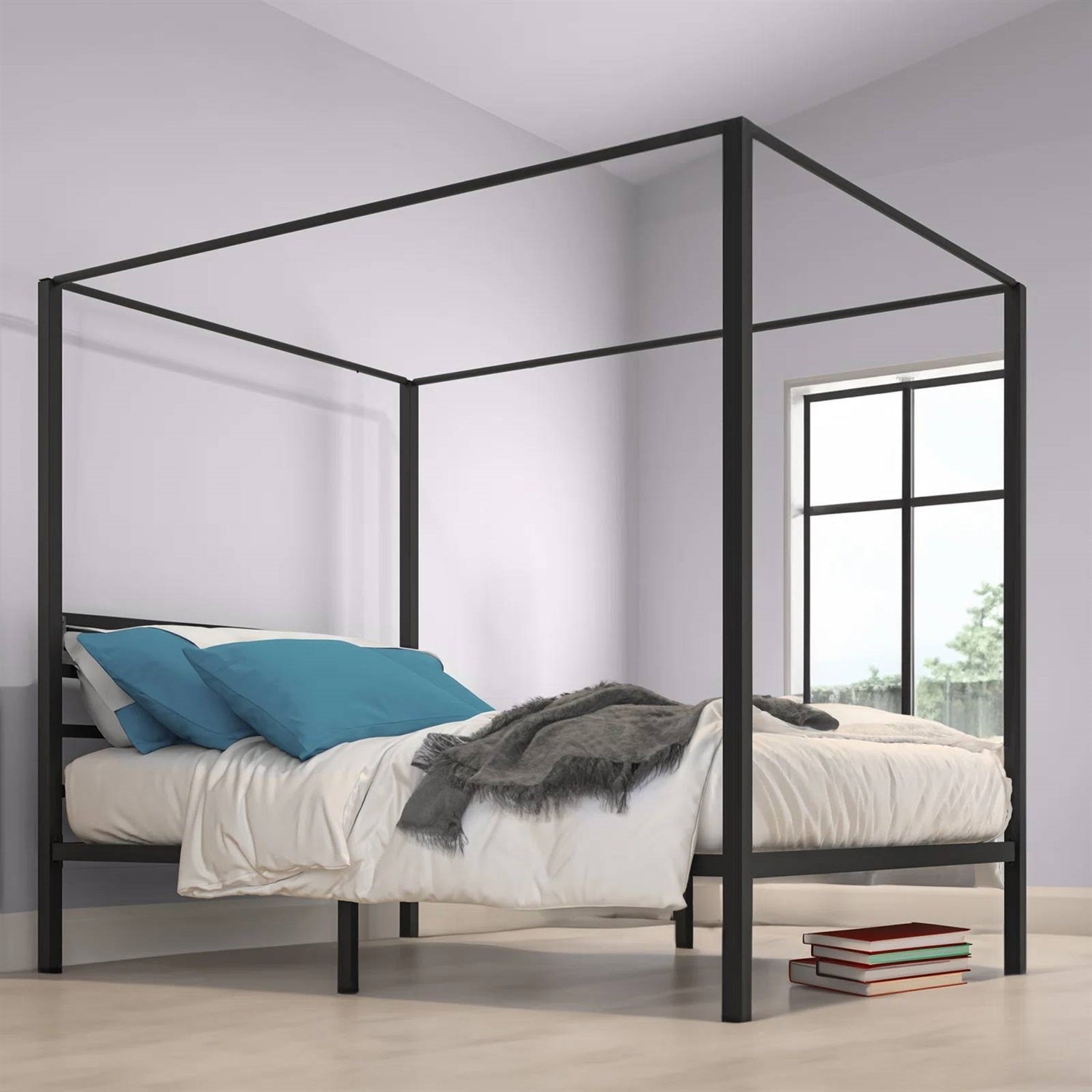 Black metal canopy bed with bedding in a room with a window.
