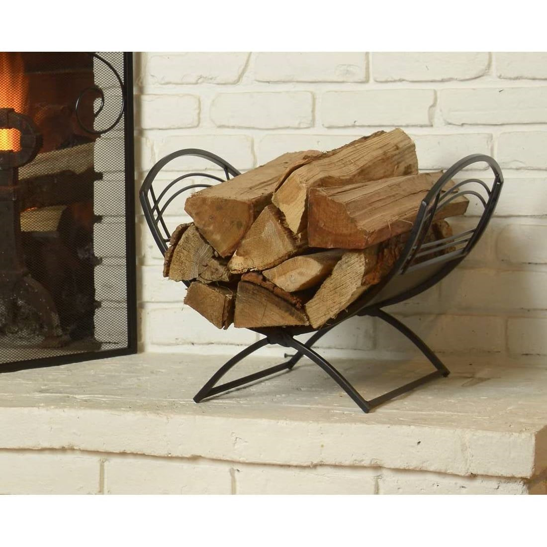 Firewood in a metal basket in front of a fireplace with white brick wall.