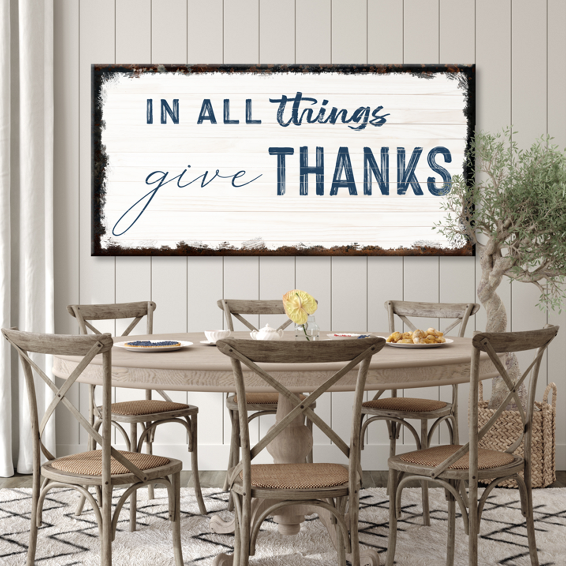 Dining room with a table and chairs, and a large framed sign above it with the text 'In all things give thanks'.