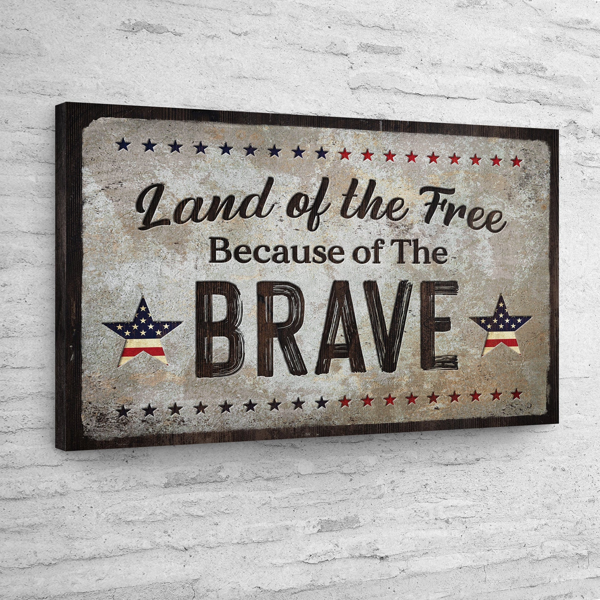 Decorative sign with 'Land of the Free Because of The Brave' text on a textured wall.
