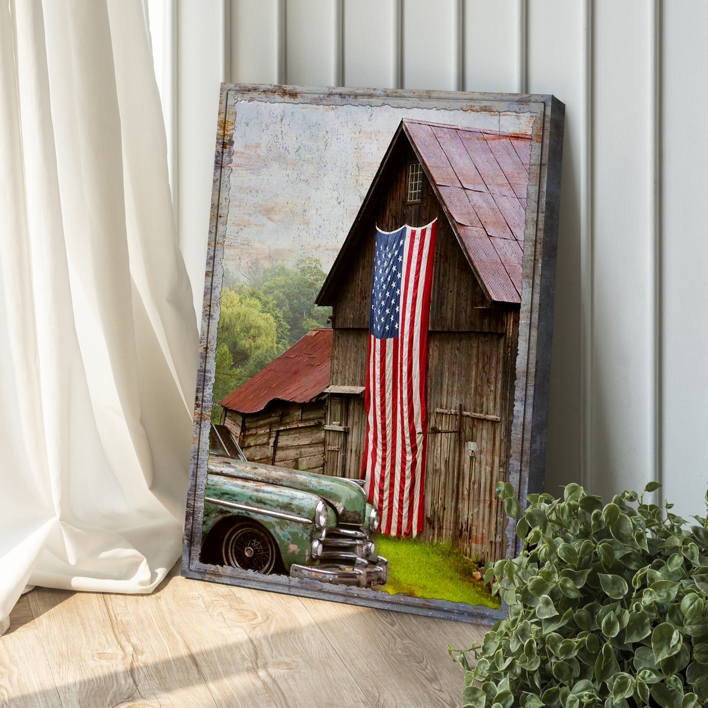 Framed artwork of a barn with an American flag and a vintage car on a wooden floor.