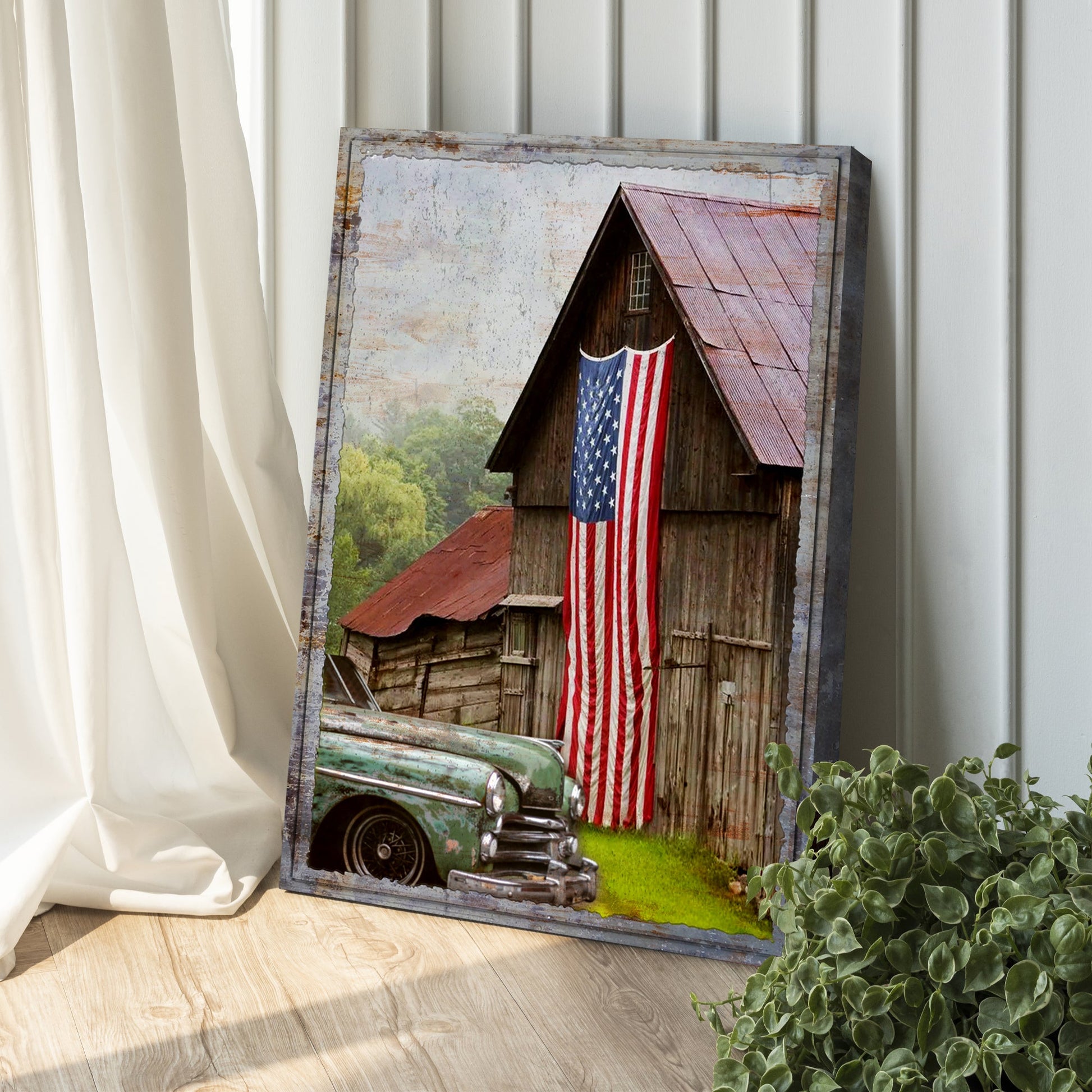 Framed artwork of a barn with an American flag and a vintage car on a wooden floor.