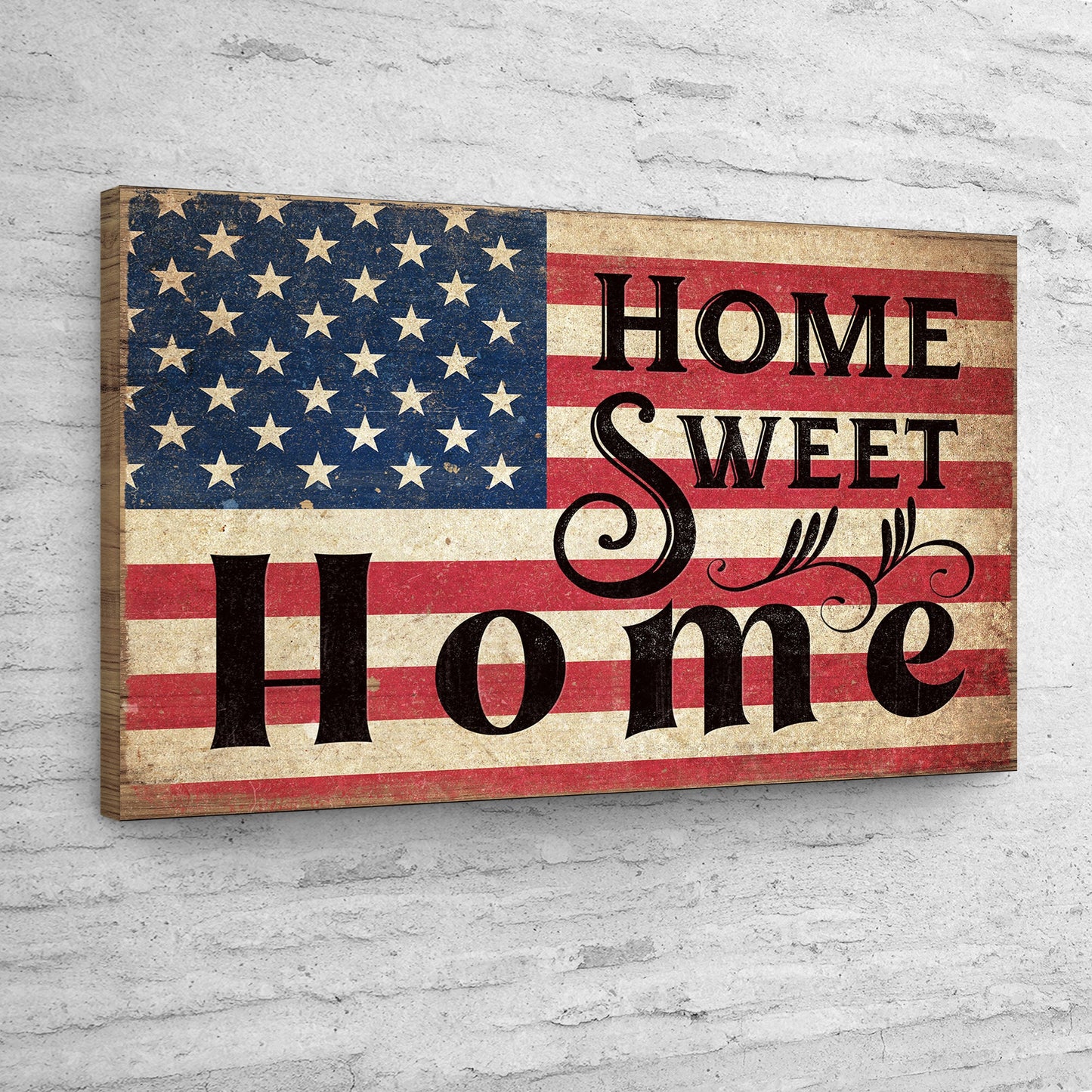 Decorative sign with American flag and 'Home Sweet Home' text on a white brick wall.