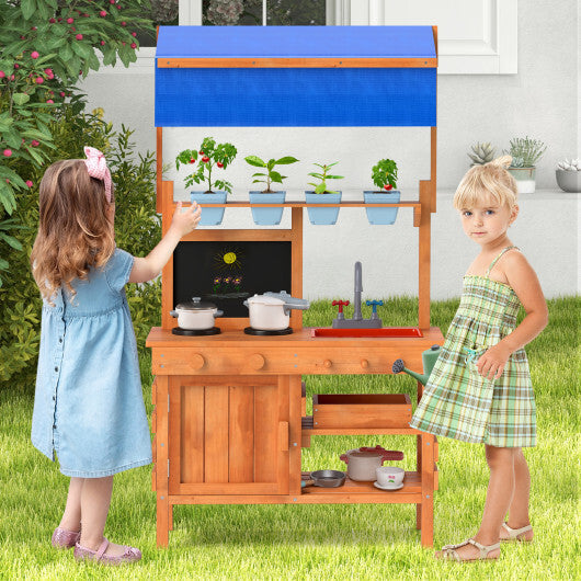 Children playing with a wooden play kitchen set outdoors.