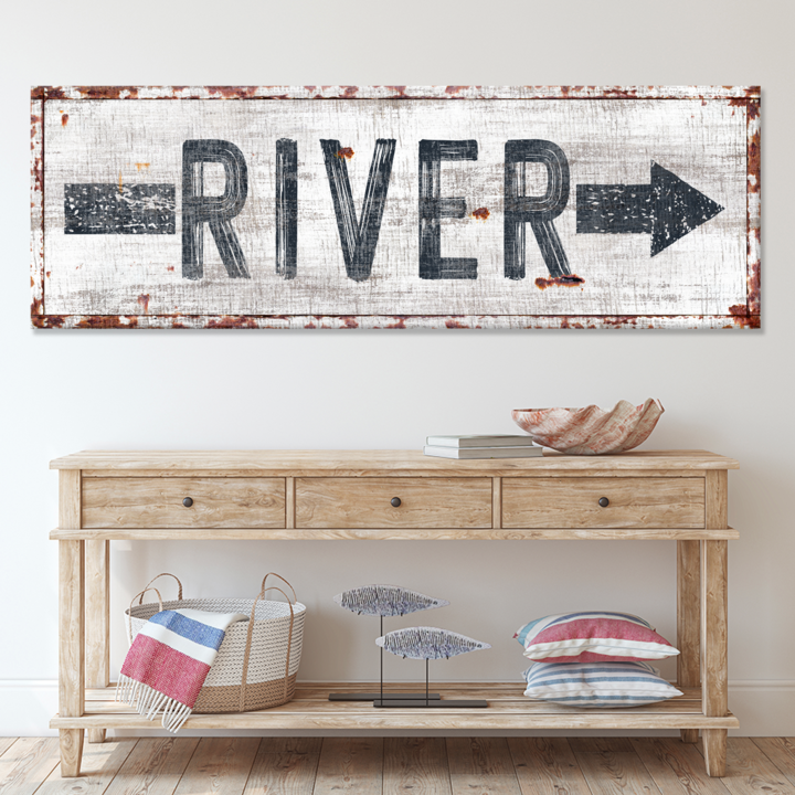 Wooden console table with decorative items against a white wall with a 'River' sign.