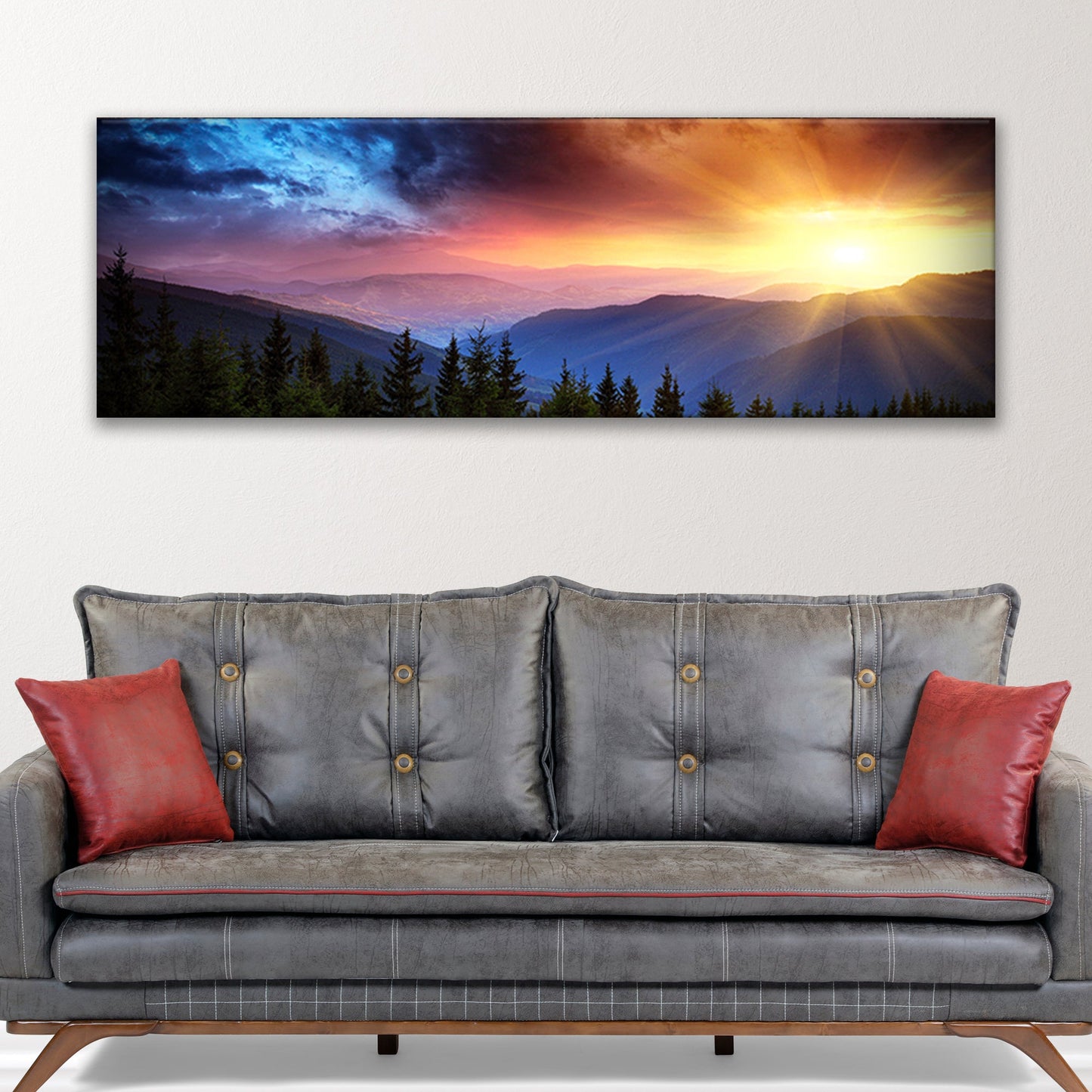 Gray sofa with red pillows in front of a large mountain sunset print.