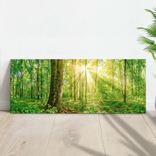 Canvas print of a forest scene with sunlight filtering through the trees, placed on a wooden floor.