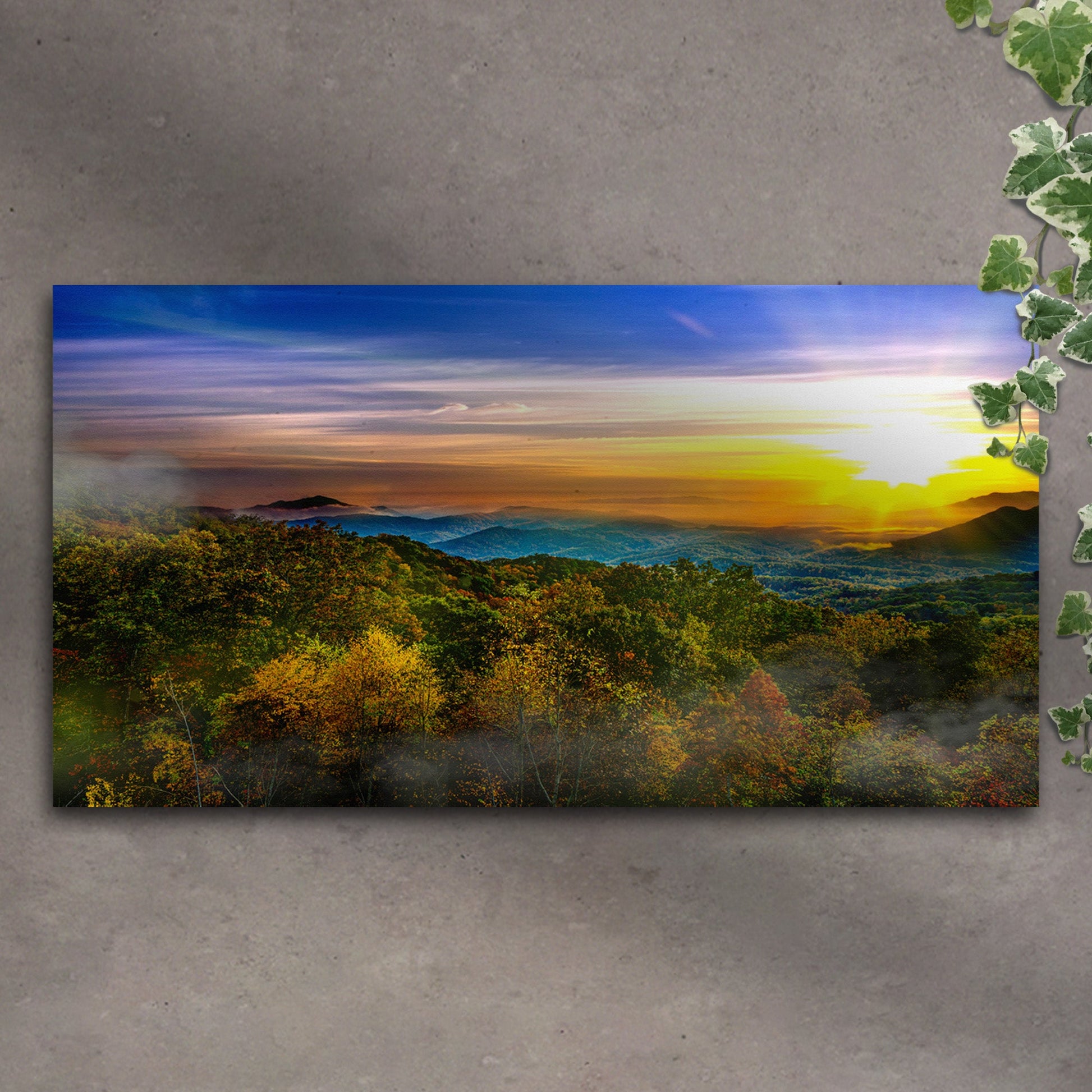 Landscape print of a sunset over a forest on a textured wall.
