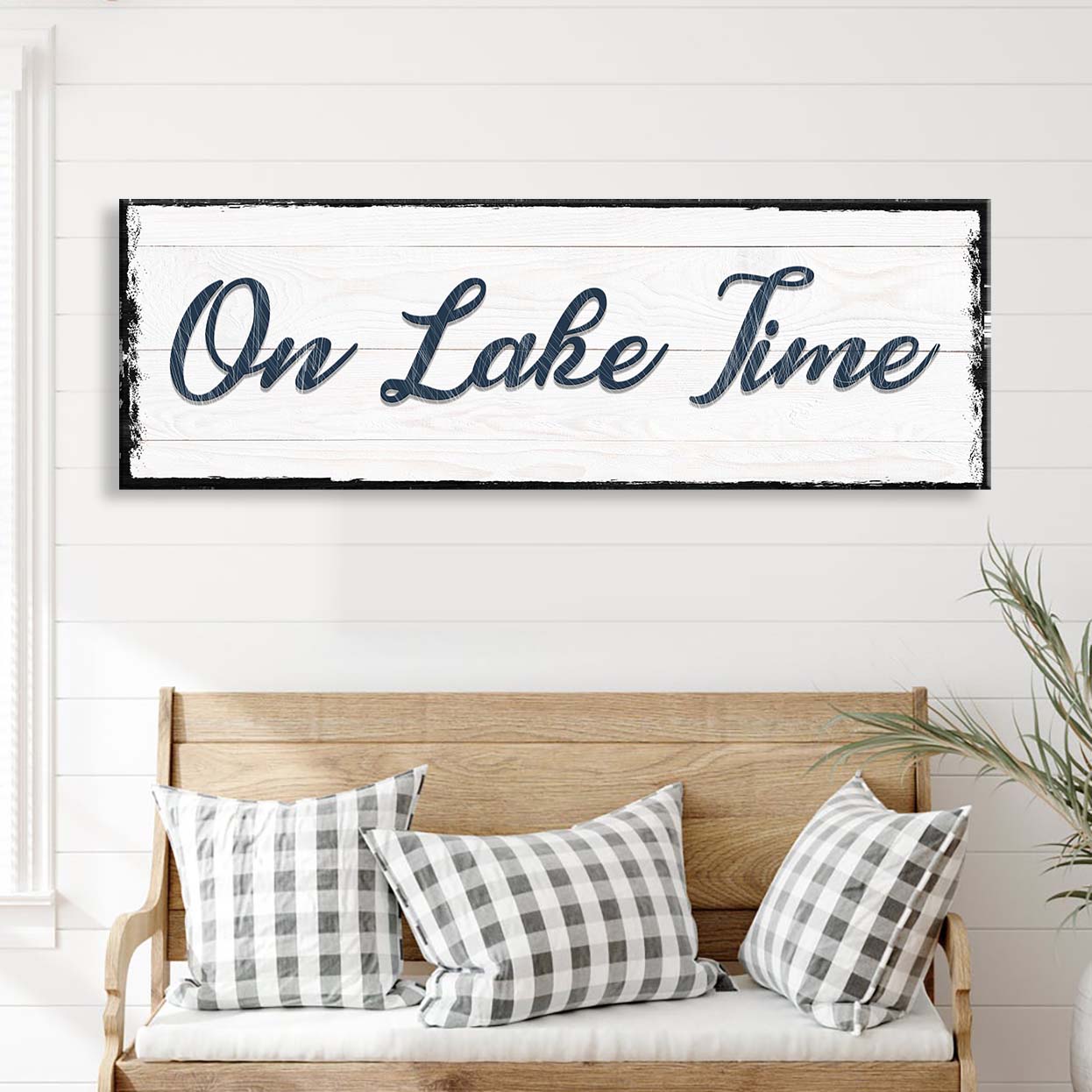 Decorative sign with 'On Lake Time' text above a wooden bench with checkered pillows.
