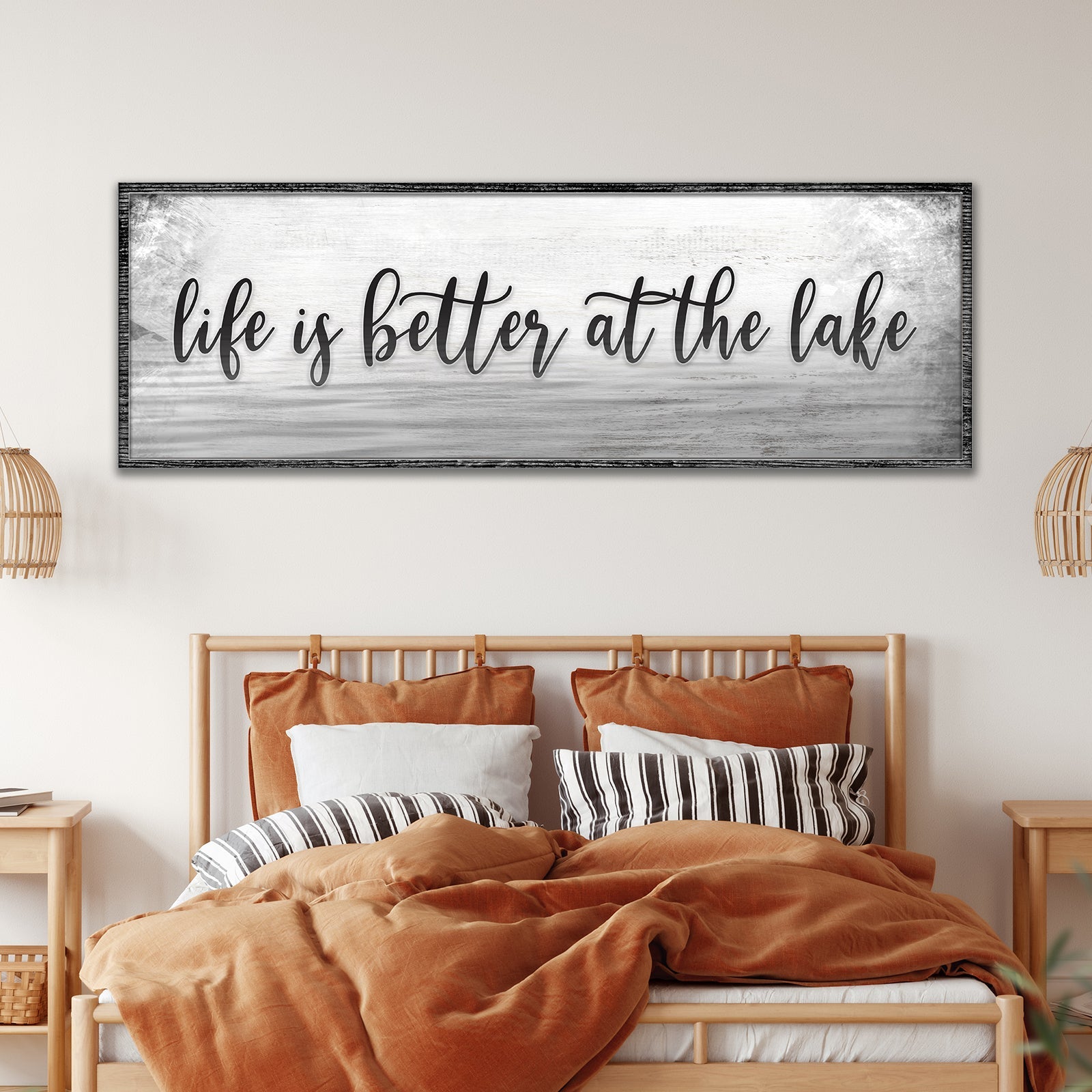 Bedroom with 'life is better at the lake' wall art above a bed.