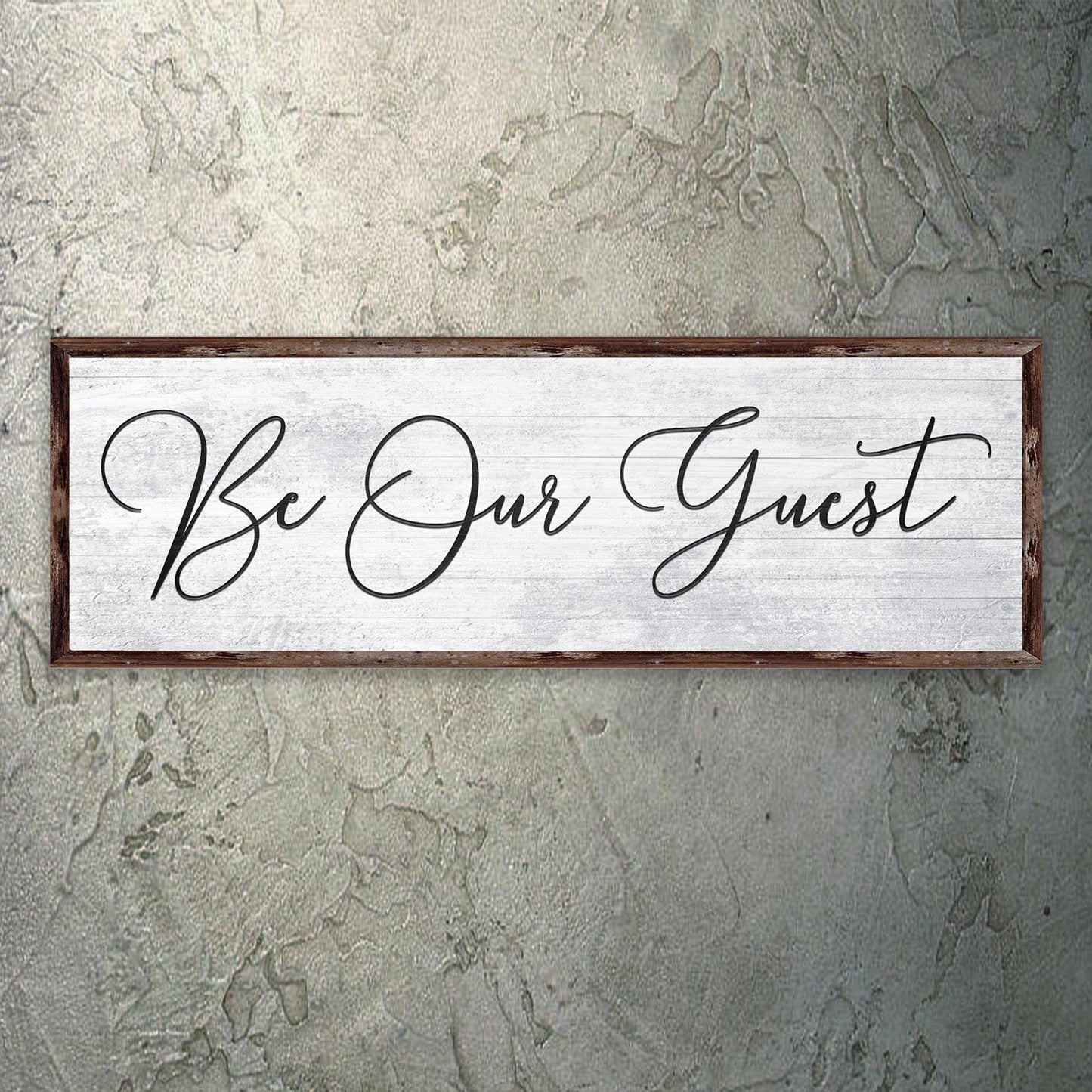 Decorative sign with 'Be Our Guest' text on a textured wall.