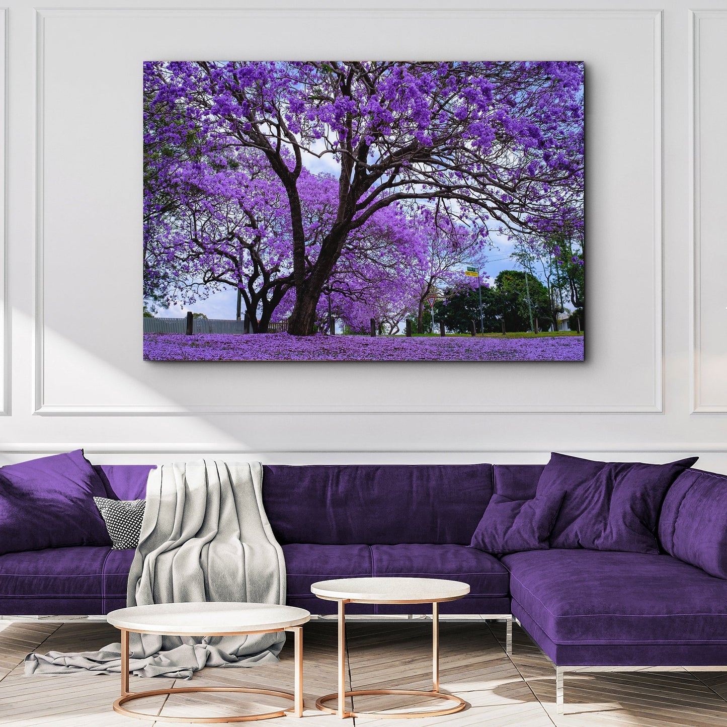 Purple floral painting on a wall above a purple sofa in a living room.