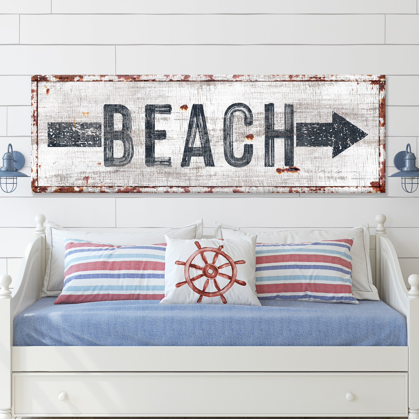 Decorative sign with 'BEACH' and an arrow above a bed with nautical-themed pillows.