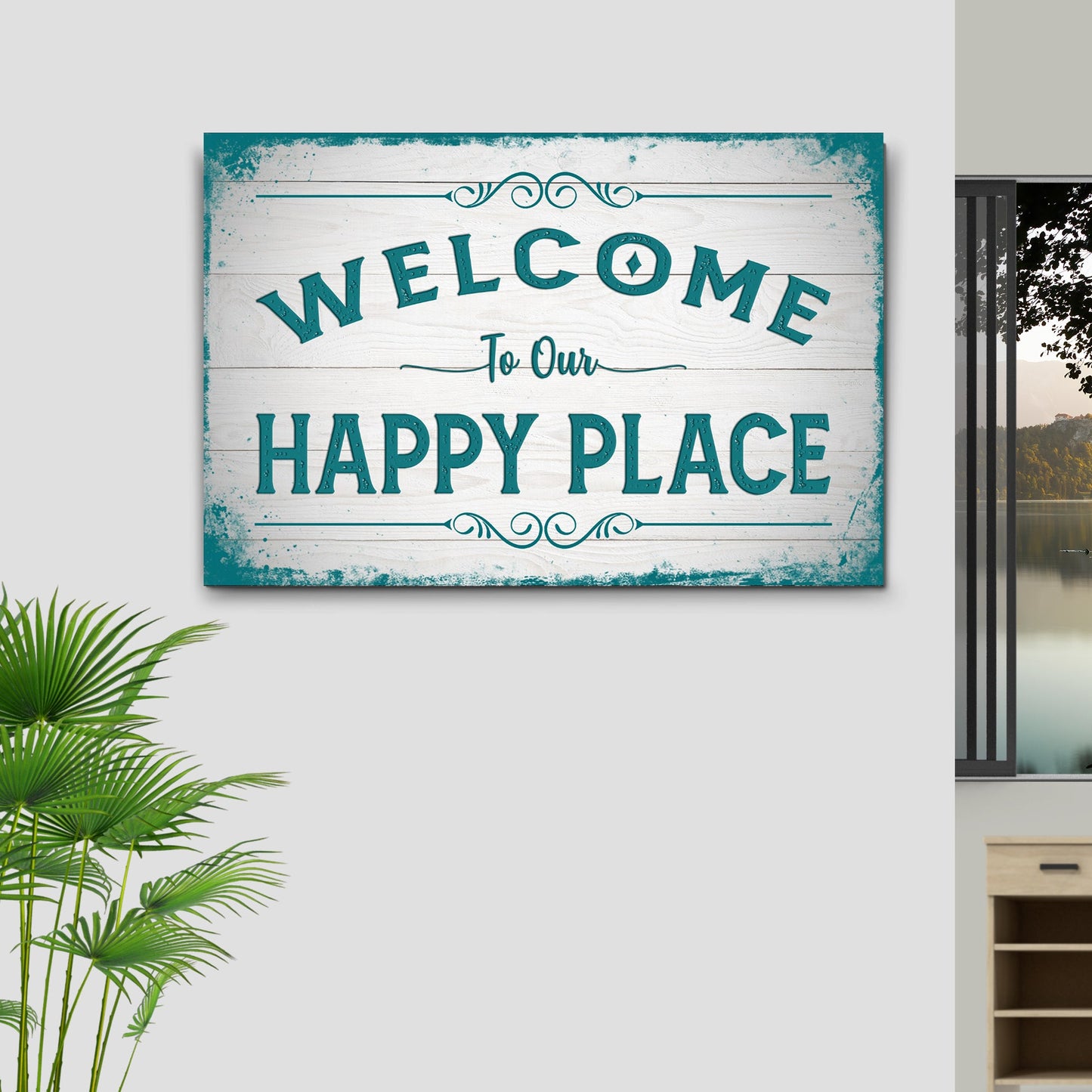 Decorative sign with 'Welcome to Our Happy Place' text on a wall with a plant and window in the background.
