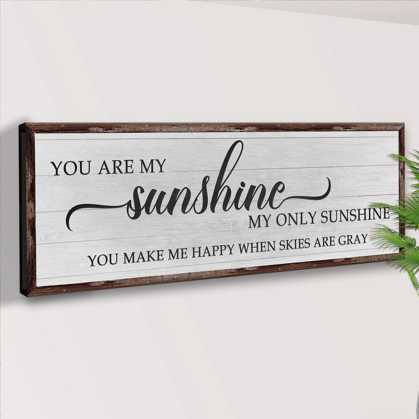 Wooden sign with text 'You are my sunshine, my only sunshine' on a white wall.