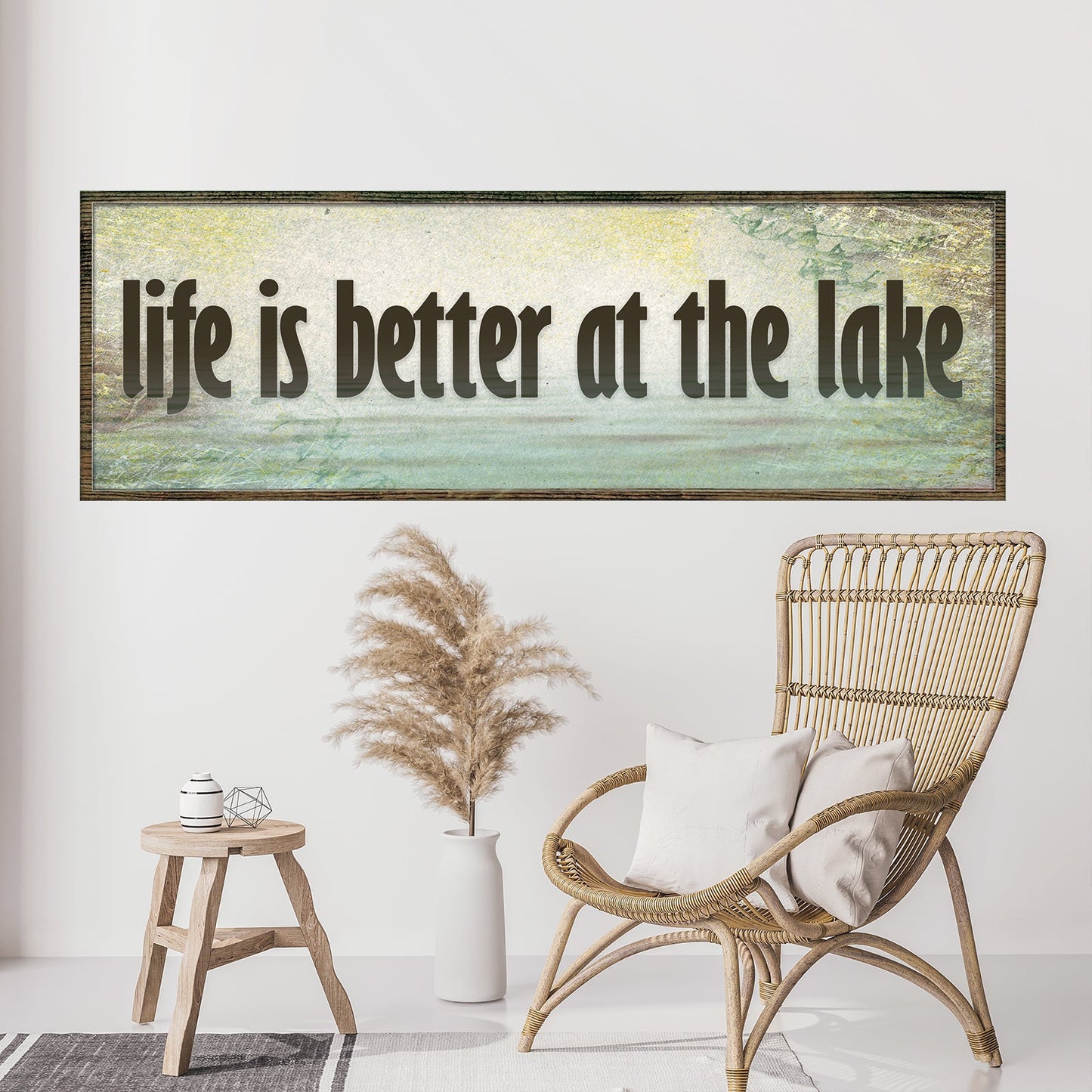 Framed artwork with 'life is better at the lake' text above a wicker chair and decorative items.