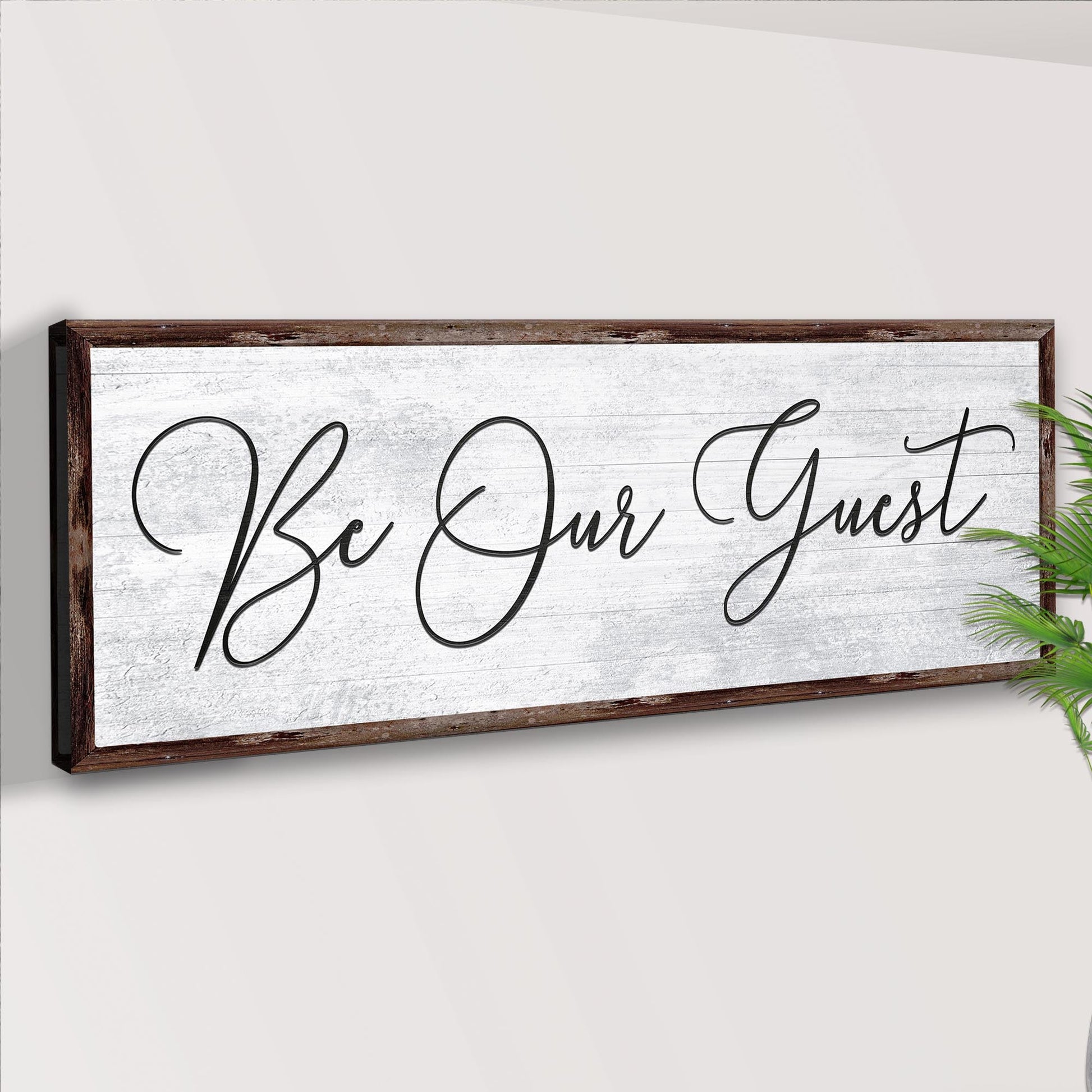 Decorative sign with 'Be Our Guest' text on a white background