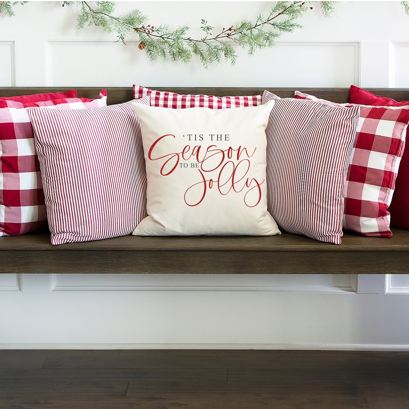 Tis the Season To Be Jolly Pillow Cover on a stylish wooden bench with festive pillows in red and white.