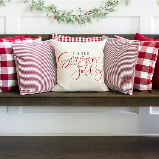 Tis the Season To Be Jolly Pillow Cover on a stylish wooden bench with festive pillows in red and white.