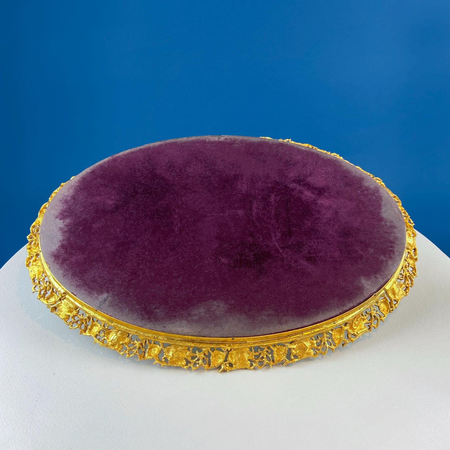 Round purple cushion with gold decorative frame on a blue background