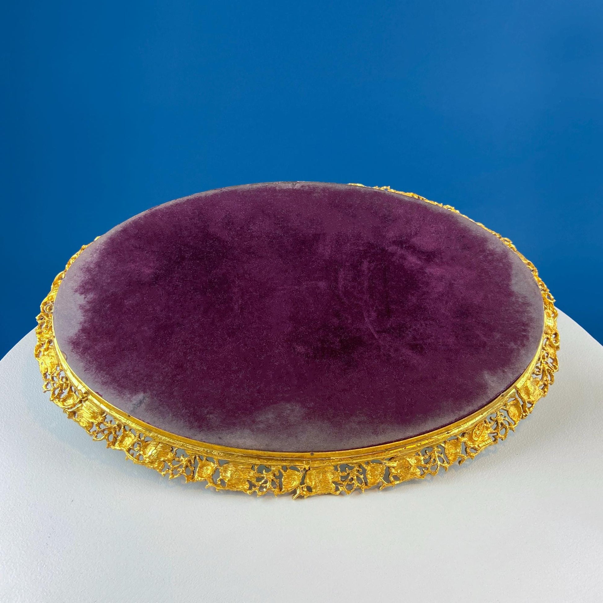 Round purple cushion with gold decorative frame on a blue background