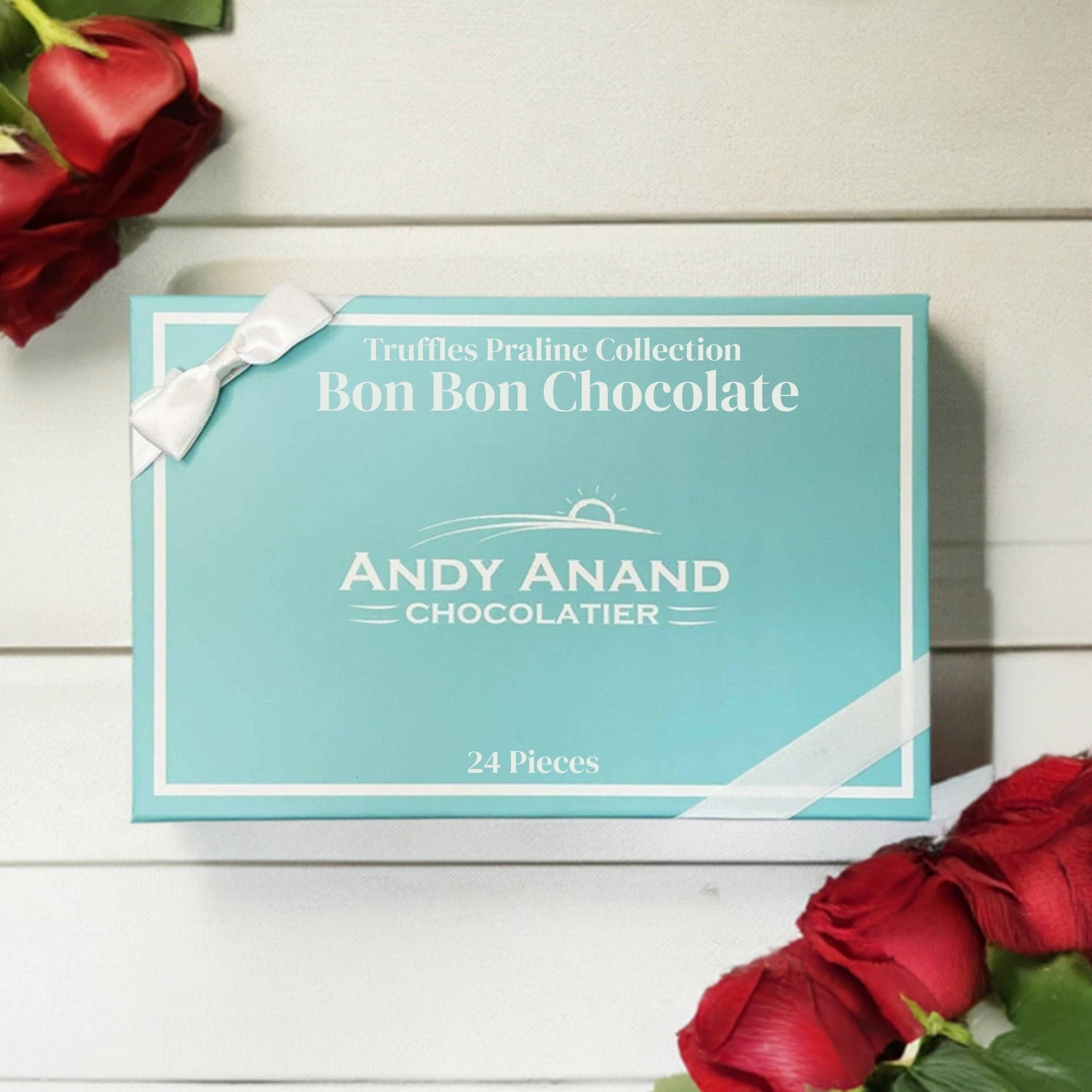 Box of Andy Anand Chocolatier Bon Bon Chocolate with red roses on a wooden surface