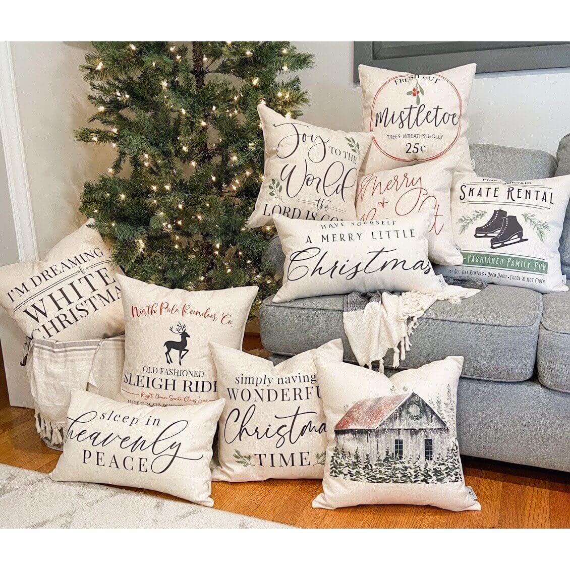 Gray Barn with Trees Pillow Cover 17x17 inch among decorative pillows on a cozy couch for the holidays.