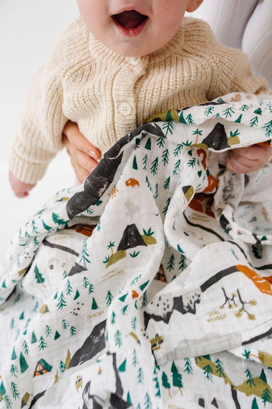 Baby holding a blanket with animal patterns on a white background