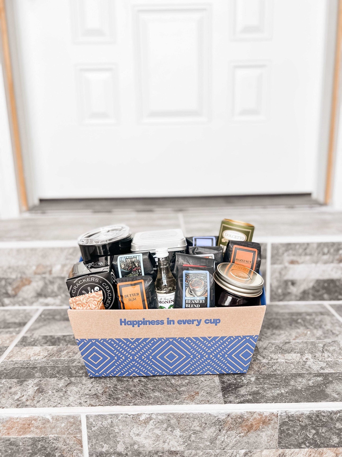 Gourmet Favorites Gift Basket filled with premium coffee and gourmet snacks, placed on stone steps.