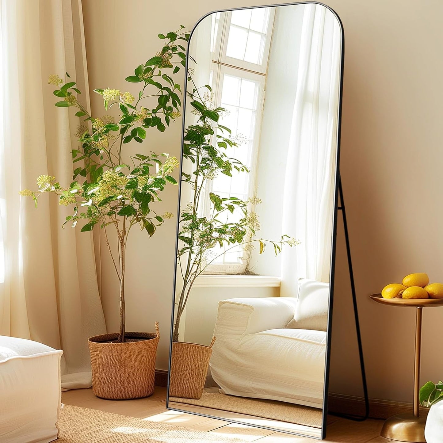 71 Inch Black Oversized Full Length Arch Floor Mirror reflecting a bright, stylish room with plants and natural light.