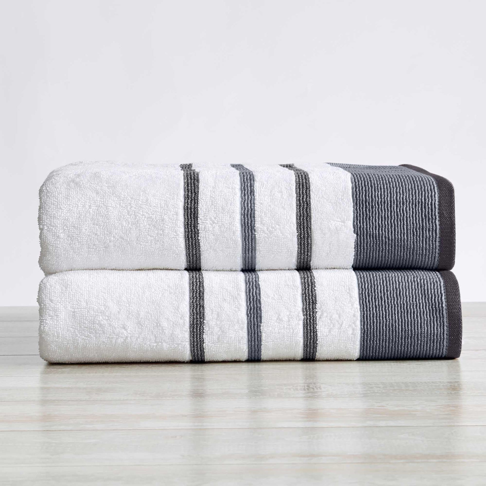 Two folded towels with gray and white stripes on a light wooden surface.