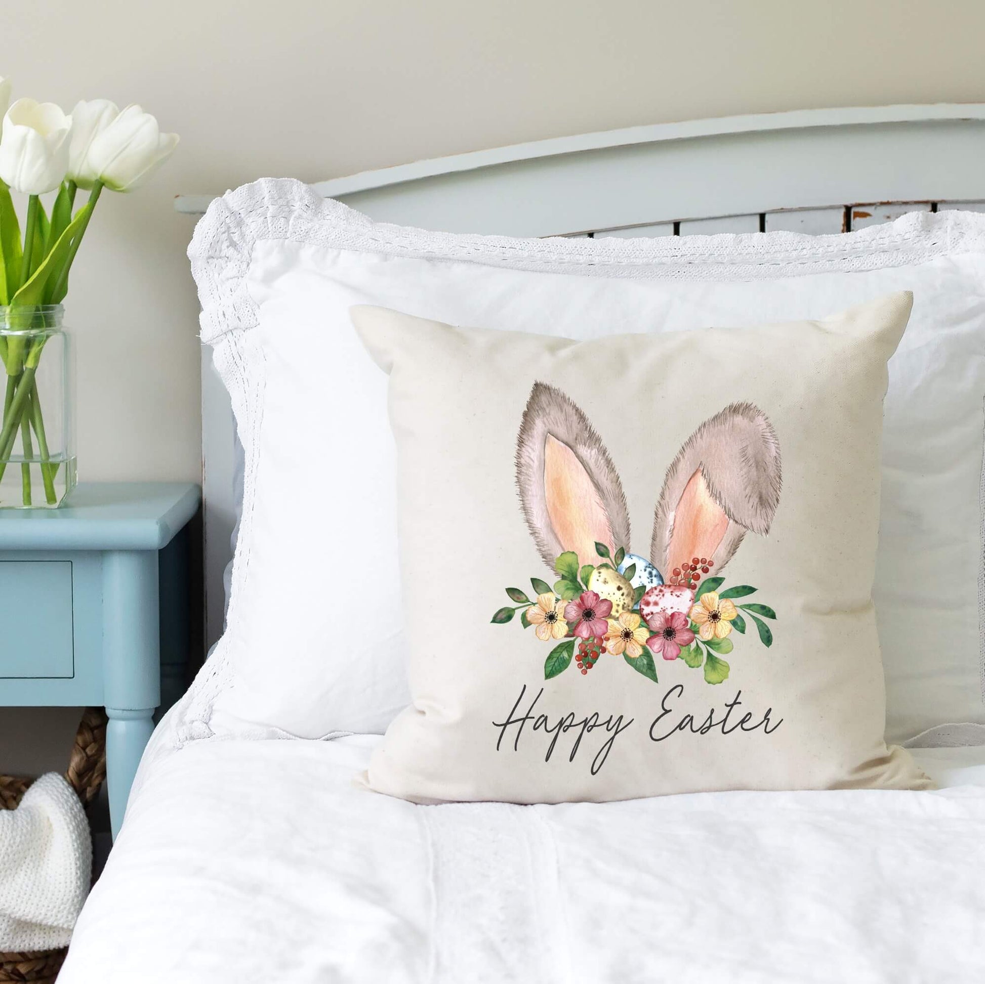 Happy Easter Bunny Ears Pillow Cover 18x18 inch displayed on a bed with floral decoration.