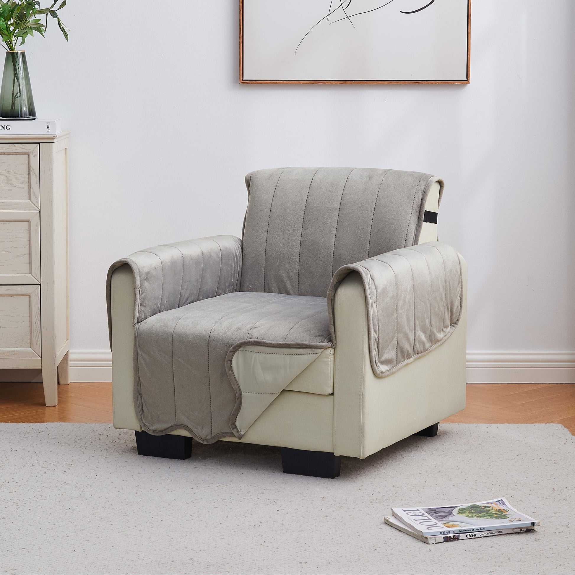 Chair with a gray cover in a room with a cabinet and plant.