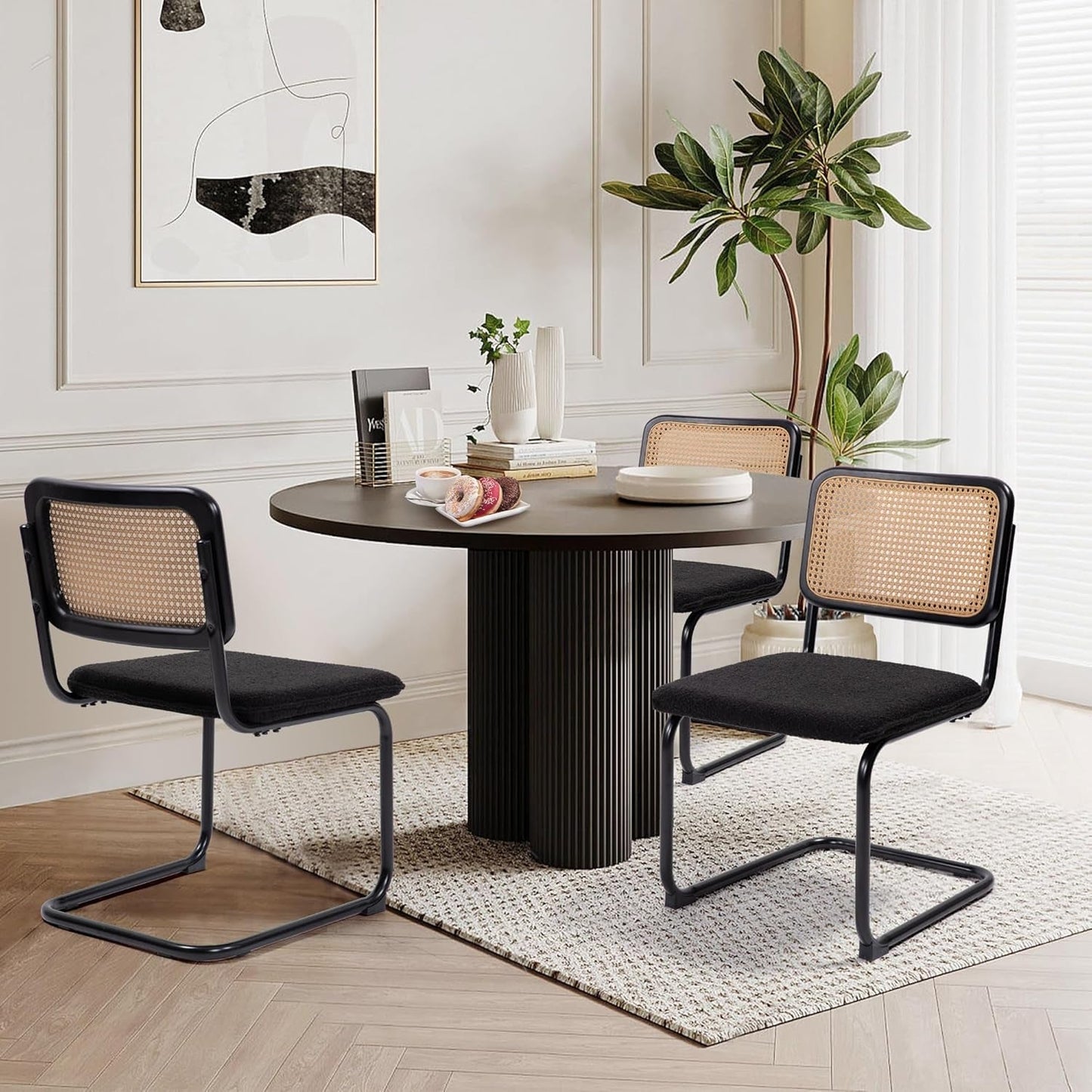 Cesca Cane Dining Chairs Set of 2 Black Boucle Seat around a modern dining table with plants and decor.