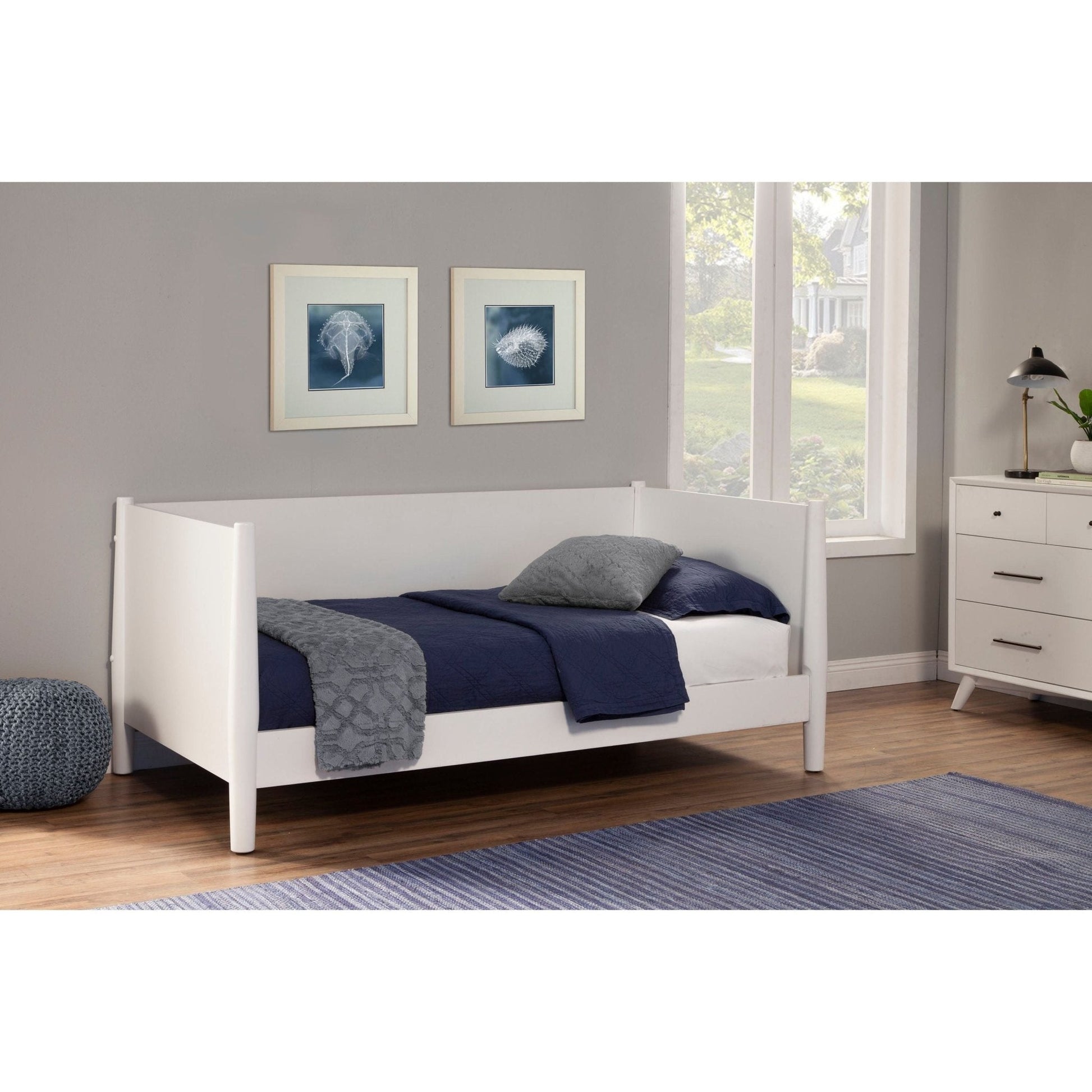 Flynn Day Bed in white, featuring a modern design with blue bedding and framed artwork on the wall.